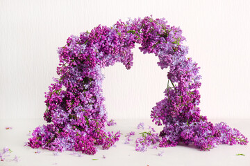 Arch made of beautiful lilac flowers on light background