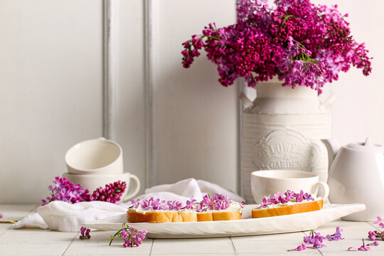 Plate Of Sandwiches With Tasty Cream Cheese, Lilac Flowers And Tea Set On Light Table