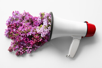 Creative composition with megaphone and beautiful lilac flowers on light background