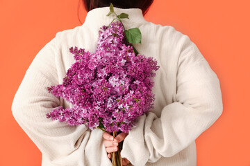 Young woman with bouquet of lilac flowers on red background