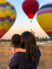 Mother and her baby looking at a beautiful view full of balloons on Mother's Day - obrazy, fototapety, plakaty