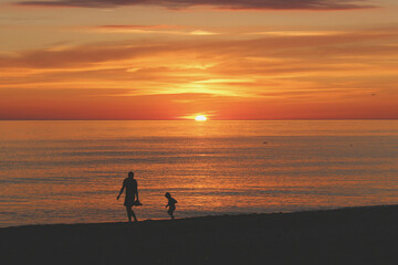 Mother and son running laughing through the brightest sunset on Mother's Day - obrazy, fototapety, plakaty