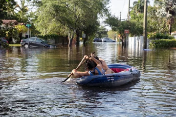 Foto op Canvas COUPLE IN AN INFLATABLE RAFT NAVIGATES FLOODED STREETS © Mike Butler