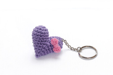 A single crocheted purple heart-shaped keyring on a textured background