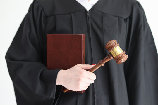 Judge in gown holds constitution and wooden gavel in studio