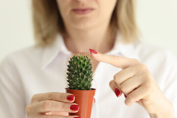 Woman touches cactus thorns with finger in light studio © megaflopp