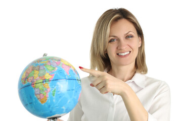 Positive blonde woman points to Earth globe in light studio