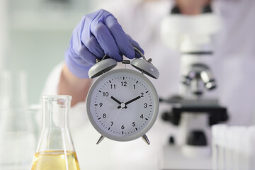 Scientist in gloves measures time for conducting experiment