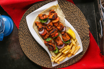 Shish Tawook or tikka kabab with fries, lemon and bread served in dish isolated on red mat top view...