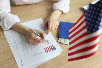 Young woman fills in visa application form near USA flag