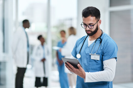 Medical, doctor and tablet with a man in a clinic reading healthcare and wellness data at hospital. Employee, nurse and Indian male person with digital and health results on technology with research