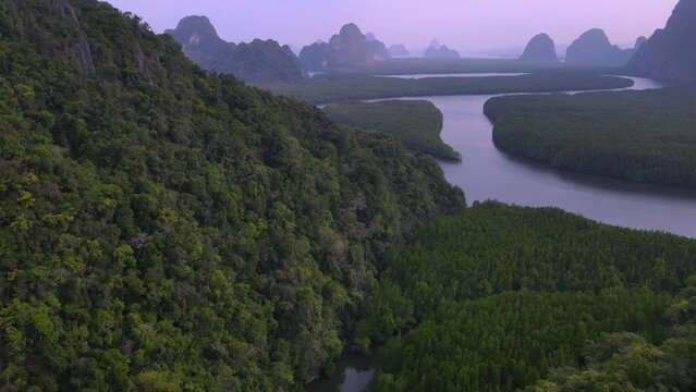 Aerial top view of mountain valley hills, and tropical green forest trees at sunset with Andaman sea in Phang Nga Bay.camera paning up movement forword