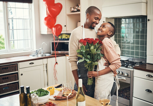 Flowers, love and valentines day with a black couple in the kitchen for a romantic celebration together. Food, gift or romance with a man and woman bonding in their home during a special event