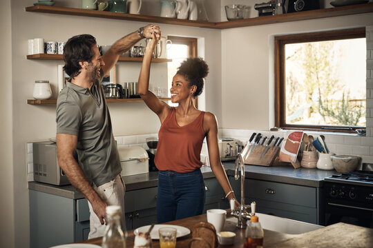 Happy couple, dance and fun bonding in kitchen for romance, love or holiday together at home. Interracial man and woman dancing in happiness for romantic relationship or enjoying weekend in the house