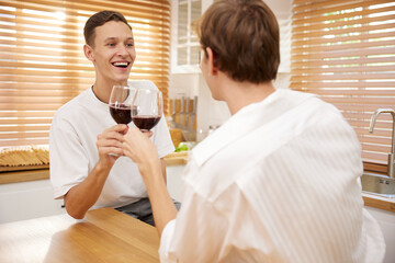 LGBT gay couple talking with boyfriend and drinking wine in dining room