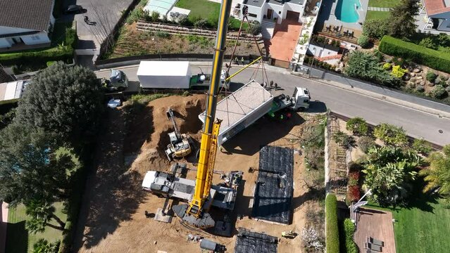 Crane lifting module of prefab house from truck. Aerial circling, high angle