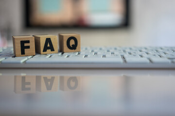 FAQ message on the wooden cube placed on the keyboard. Acronym faq of frequently asked questions