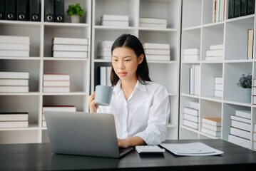 Confident Asian woman with a smile standing holding notepad and tablet at the office..