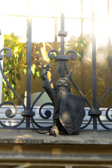 Dwarf on the street corner with a shield. Small bronze figures of gnomes on the streets of Wroclaw. Europe Miniature bronze figure of a gnome. Symbol of Wroclaw. Tourist attraction  - obrazy, fototapety, plakaty