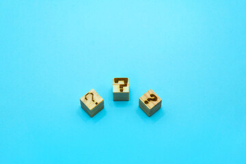 青い背景上に3つの形の違ったはてなマークのウッドキューブ