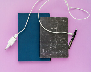 Tablet en una mesa, con su cable, y un bloc de notas.