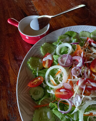 Salad with fresh vegetables on a white plate on a dark brown wooden table in a roadside cafe. 
