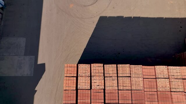 Overhead shot of piles of red bricks on construction site being loaded on lorries
