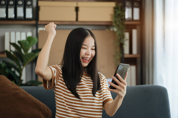 Happy Asian woman holding a smartphone and tablet happy smiling, getting bonus money.