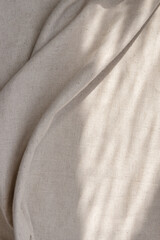 Draped beige linen fabric texture background with natural sunlight shadows, neutral lifestyle...