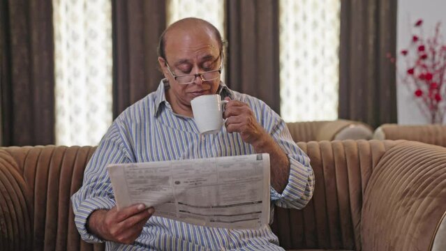 Indian old man reading newspaper in morning