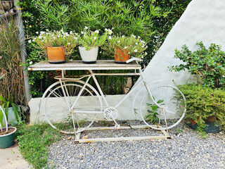 Vintage white bicycle with flower basket in the middle of the garden. beautiful decoration on...