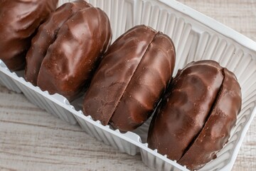 A package of marshmallows in chocolate glaze close-up lying on a wooden table. The concept of the influence of candies and sweets on dental health