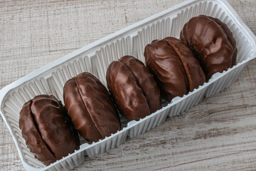 A package of chocolate marshmallows close-up lying on a wooden table. The concept of the negative impact of sweets and sweets on dental health