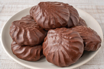 Chocolate marshmallows in a brown bowl close-up. Marshmallow in chocolate glaze close-up in a beige cup. The concept of children's caries from candies and sweets