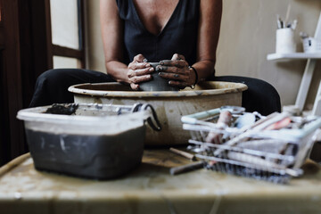 hands of latin woman potter, creating a clay pot on a pottery wheel in her workshop in Mexico Latin America, hispanic female