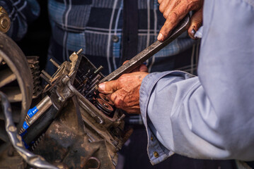 Two old men Auto mechanic working on car rusty engine in mechanics garage. Repair service close-up wrinkled dirty hands blue clothes Gear truck  Disassemble wrench home.