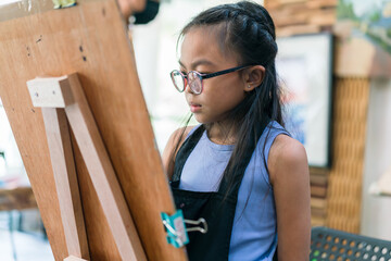 Young girl asian sitting and drawing artwork to develop abilities and improve mental health at home. Female artist drawing with inspiration.
