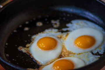 three eggs fried in frying pan scrambled eggs. Healthy food, nutritious delicious breakfast hot oil