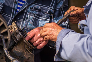 Two old men Auto mechanic working on car rusty engine in mechanics garage. Repair service close-up wrinkled dirty hands blue clothes Gear truck  Disassemble wrench home.