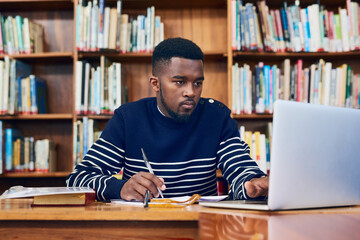 Library, laptop and university student with research, learning and planning for exam, report or focus on computer, studying or education. Black man, college and working on task, essay or scholarship - obrazy, fototapety, plakaty