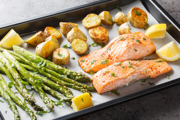 Fresh salmon fillet baked with asparagus and potatoes close-up in a baking sheet on the table. Horizontal