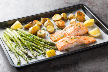 Diet food salmon fillet baked with asparagus and new potatoes close-up in a baking sheet on the table. Horizontal