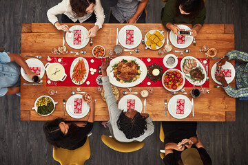 Thanksgiving, overhead and friends sitting around a table for a food meal during a celebration...