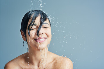 Shower, beauty and face of woman with water in studio on blue background for wellness, cleaning and...