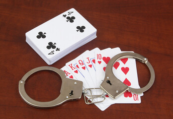 Many playing cards and handcuffs on table close up. Laws and gambling concept.	