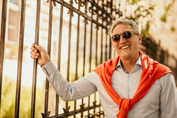 Portrait of a smiling mature man wearing a smart casual and sunglasses in the city.