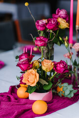 Decor details closeup. Decoration with pink, orange flowers roses, candles, fruits for birthday party, wedding reception. Luxury elegant setting dinner in a restaurant. Organized event, served banquet