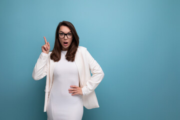 positive young business brunette woman in white office dress on blue studio background