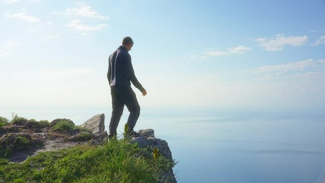 Man enoy nature and open arms on the sea cliff at day. People and nature scene.