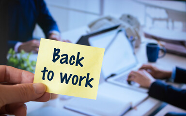 Male hand holding sticky note written Back to work.